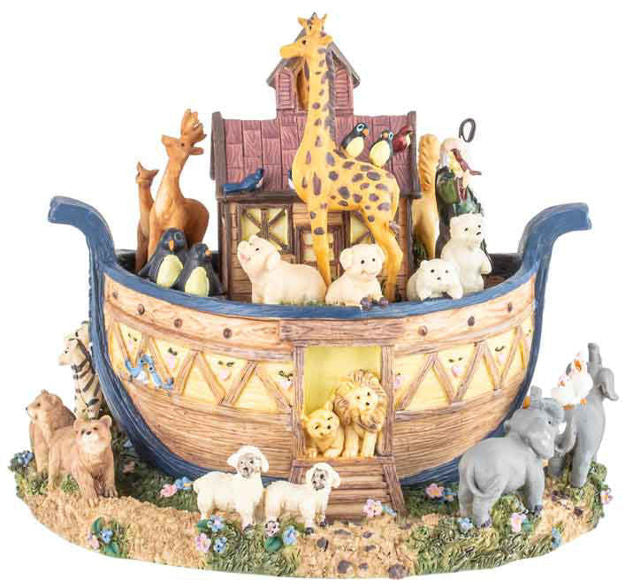 A Noah's Ark figurine featuring a detailed wooden ark with blue trim, filled with animal figures including a giraffe, lions, bears, sheep, penguins, and birds, set on a grassy base with additional animals around it.