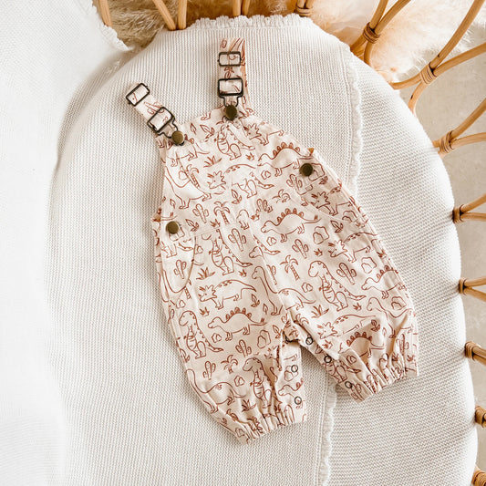 Baby romper with dinosaur pattern on a textured surface