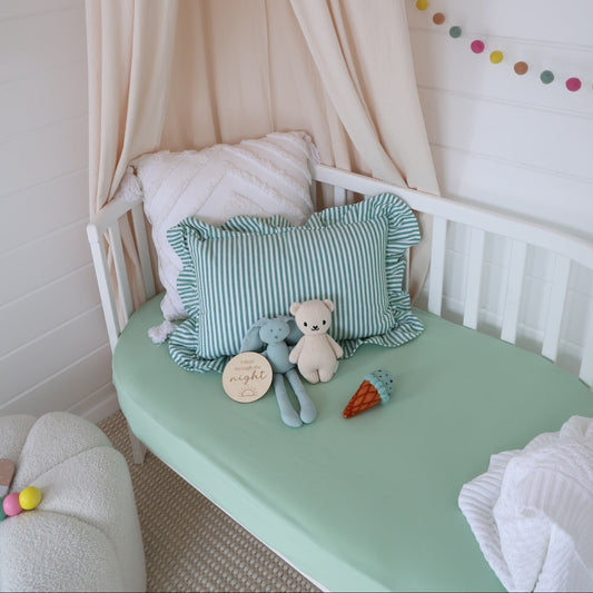 Children's reading nook with a green cushion, teddy bear, and plush carrot under a canopy.