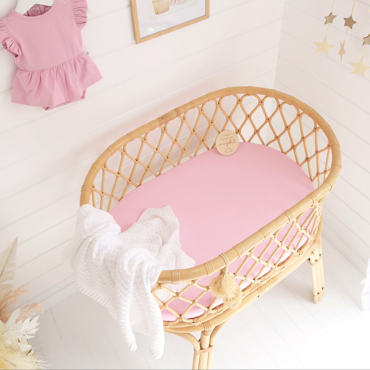 Wicker crib with pink mattress in a nursery setting