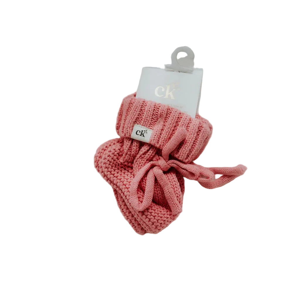 Pink knitted bow with a brand tag on a white fabric background