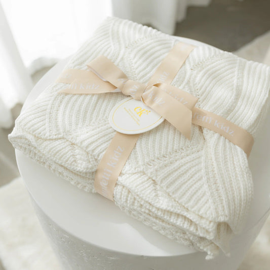 White textured blanket with a beige ribbon on a white surface