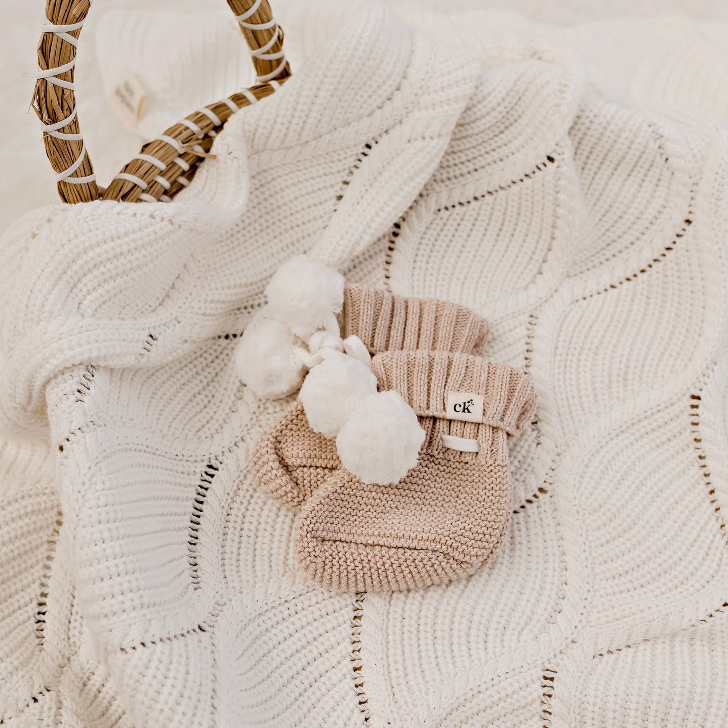 Knitted baby bootie with pom-pom on a textured blanket