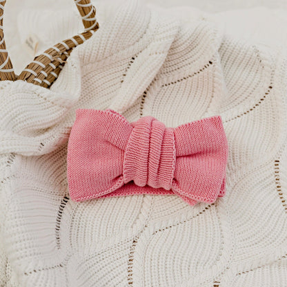Pink knitted bow on a textured white surface