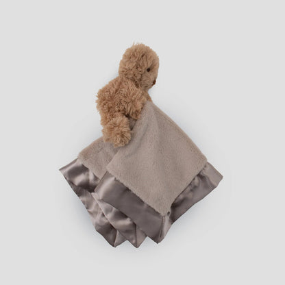 Brown plush toy on a folded brown blanket against a light gray background