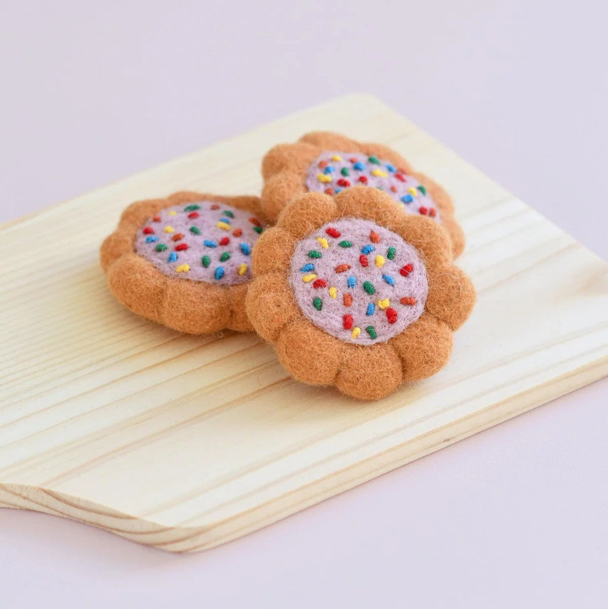Felt cookies with colorful sprinkles on a wooden surface
