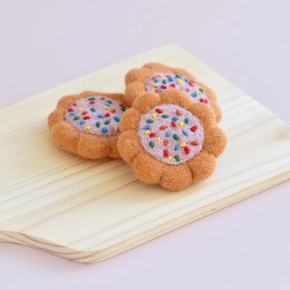 Felt cookies with colorful sprinkles on a wooden surface