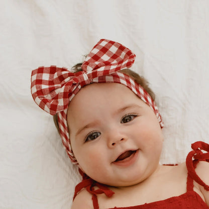 Baby wearing a red and white checkered headband on a white background