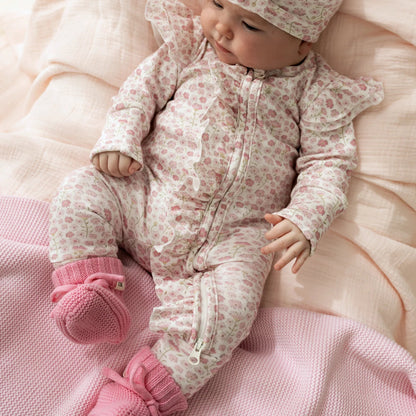 Baby in a floral outfit with a large bow on a pink blanket