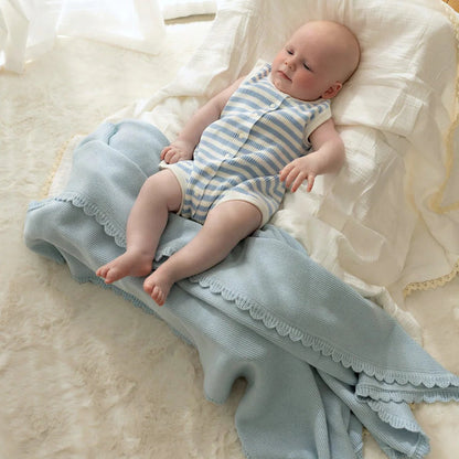 Newborn baby lying on a textured blanket with a soft white background