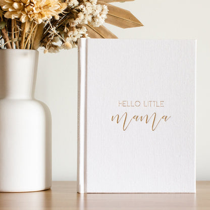 White book titled 'Hello Little Mama' with a vase of flowers on a light background