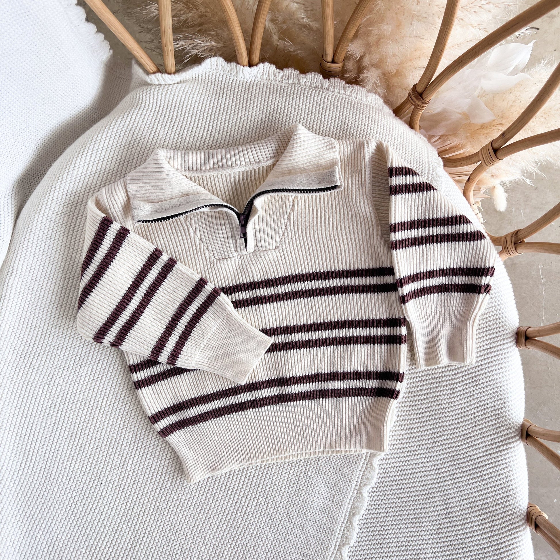 White sweater with black stripes on a textured surface