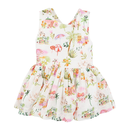 A sleeveless white baby dress with a colorful tropical print featuring palm trees, flamingos, umbrellas, and beach motifs, displayed on a solid white background.
