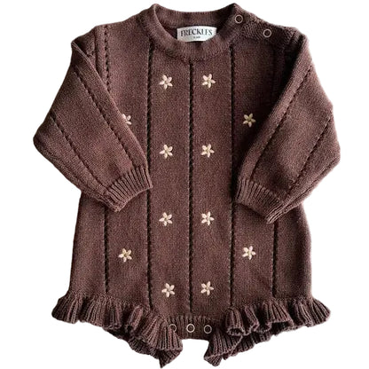 Brown knitted baby outfit with floral patterns on a light gray background