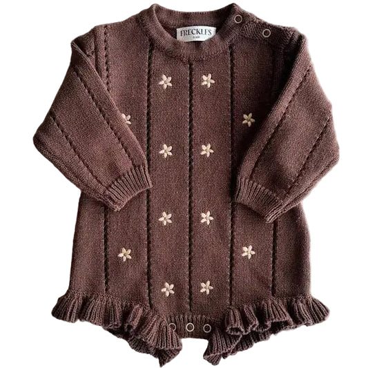 Brown knitted baby outfit with floral patterns on a light gray background