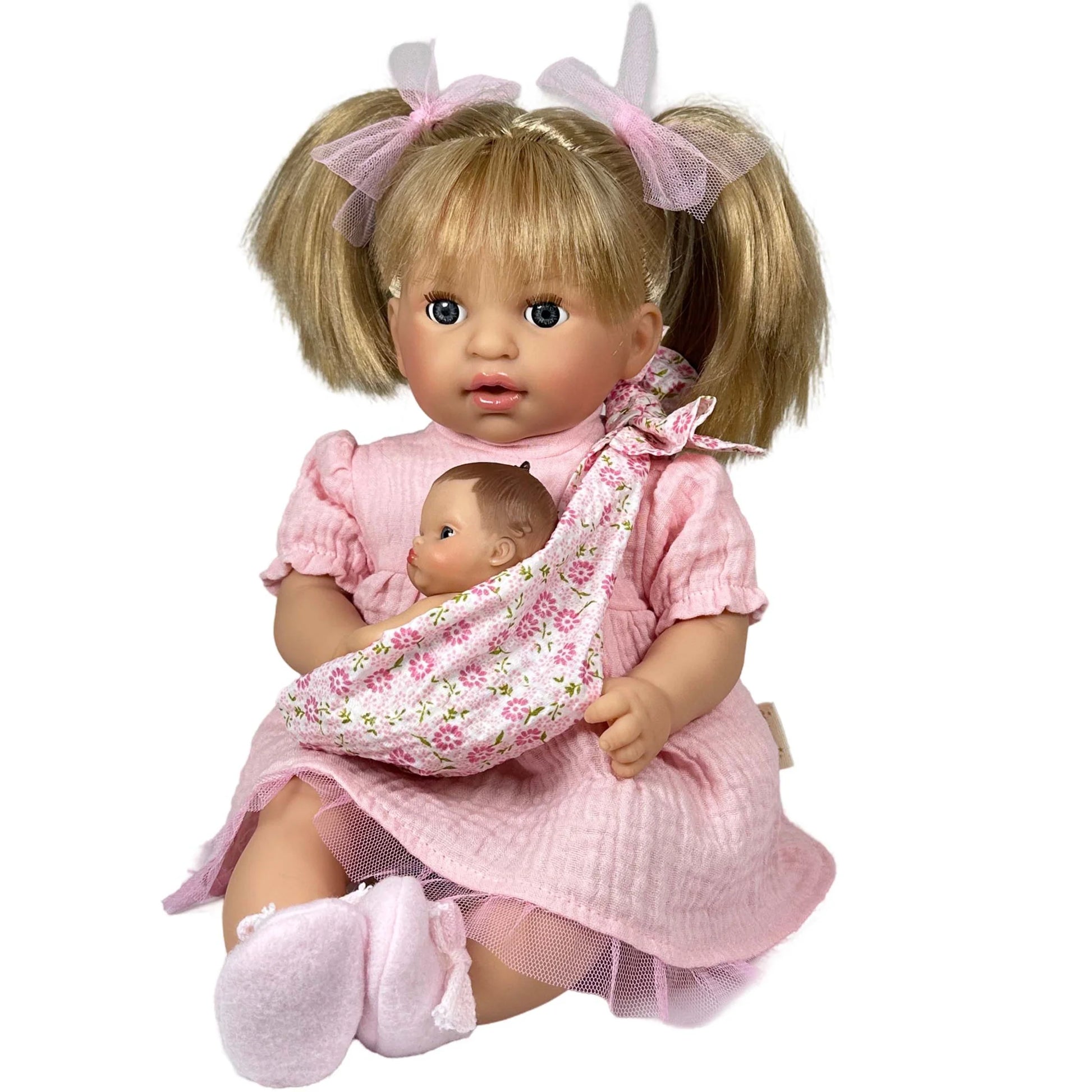 Doll in a pink dress holding a baby doll in a sling on a white background