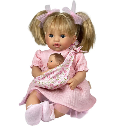 Doll in a pink dress holding a baby doll in a sling on a white background