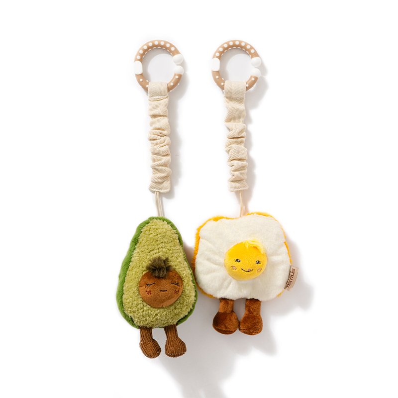 Two plush toys shaped like an avocado and a fried egg on a white background