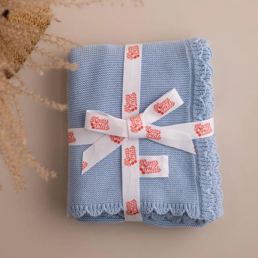 Folded blue fabric with a white ribbon and red text on a beige background
