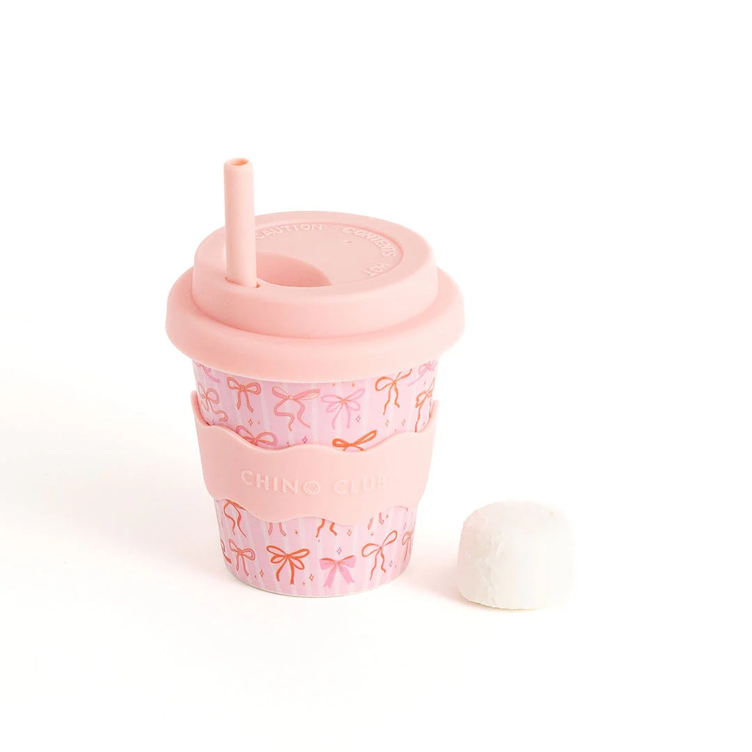 Pink tumbler with bow pattern on a white background