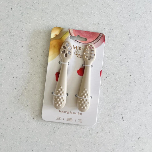 Two training spoons on a 'Mini Me' branded card against a light gray background