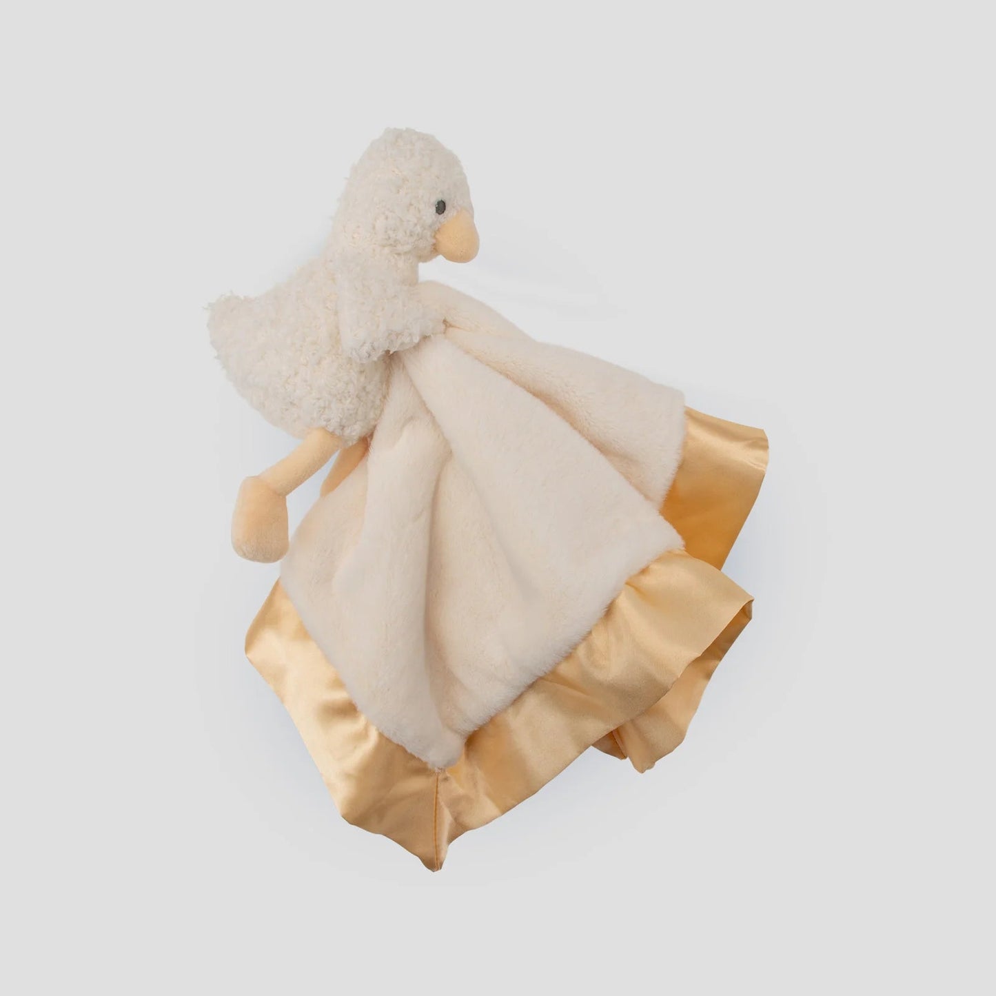 Plush toy duck with a gold and cream blanket on a light gray background
