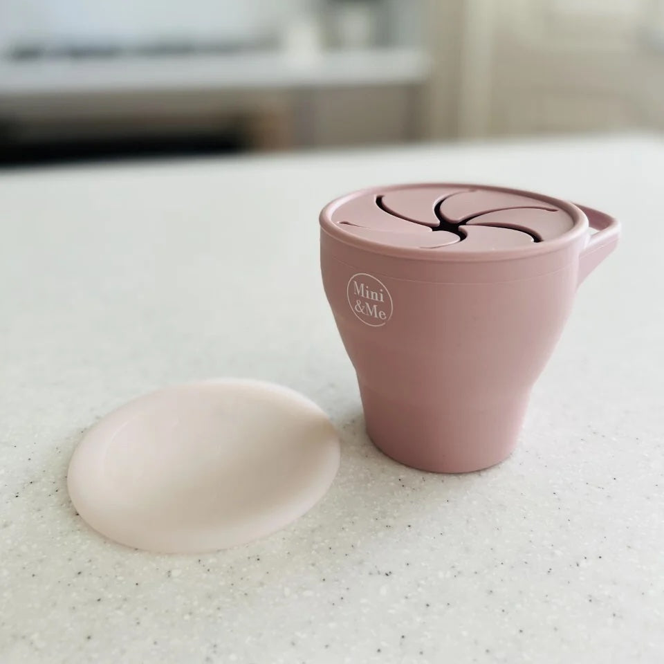 Pink ceramic pitcher with lid on a white surface