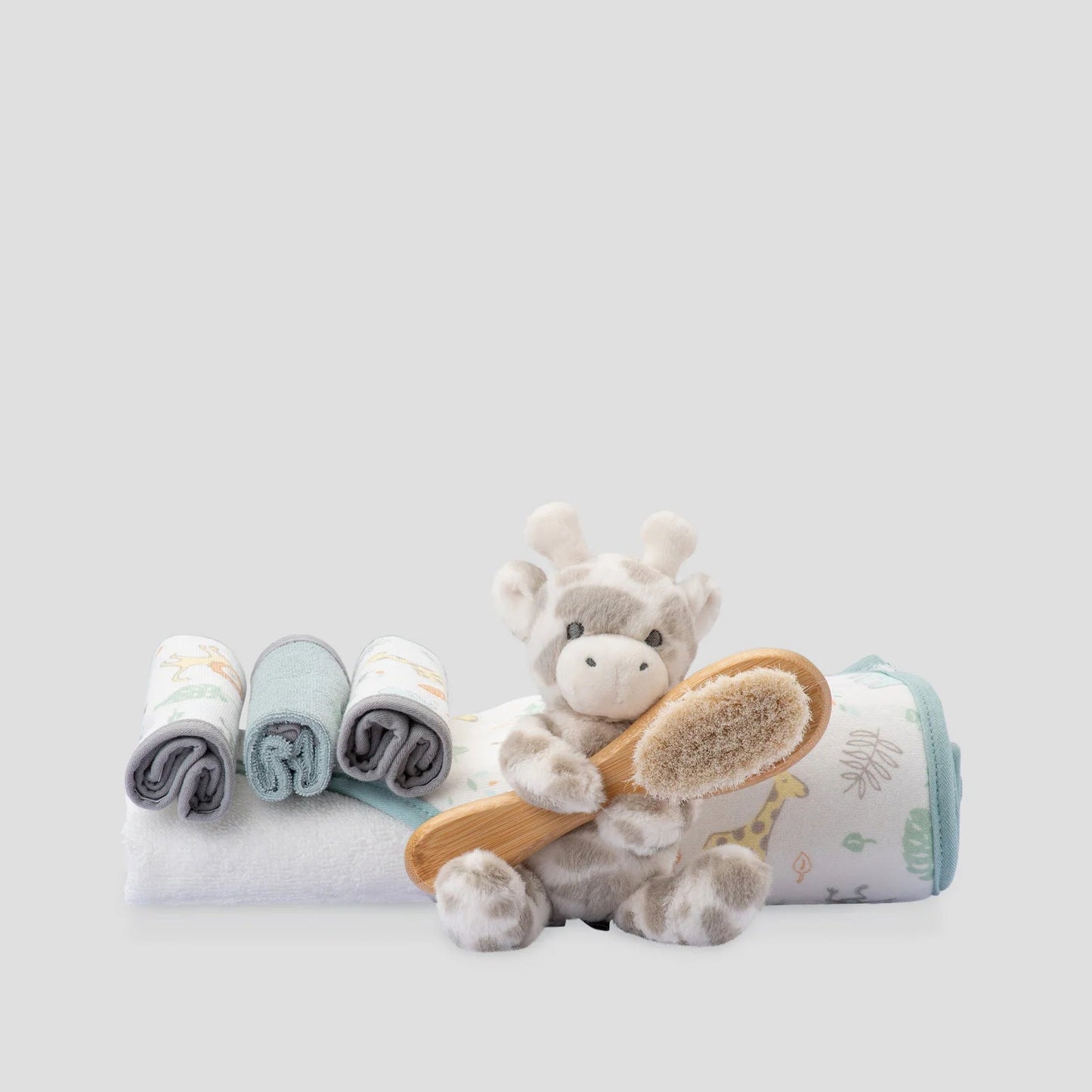 Baby care set with plush toy, washcloths, and brush on a light gray background