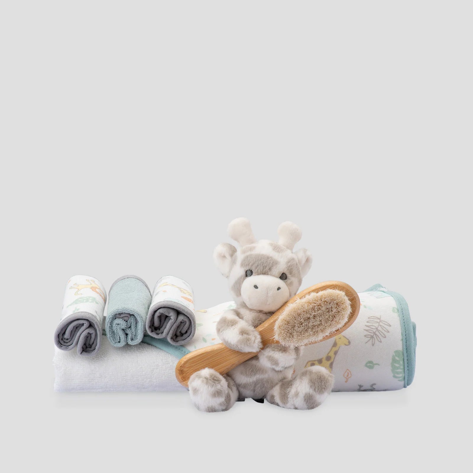 Baby care set with plush toy, washcloths, and brush on a light gray background