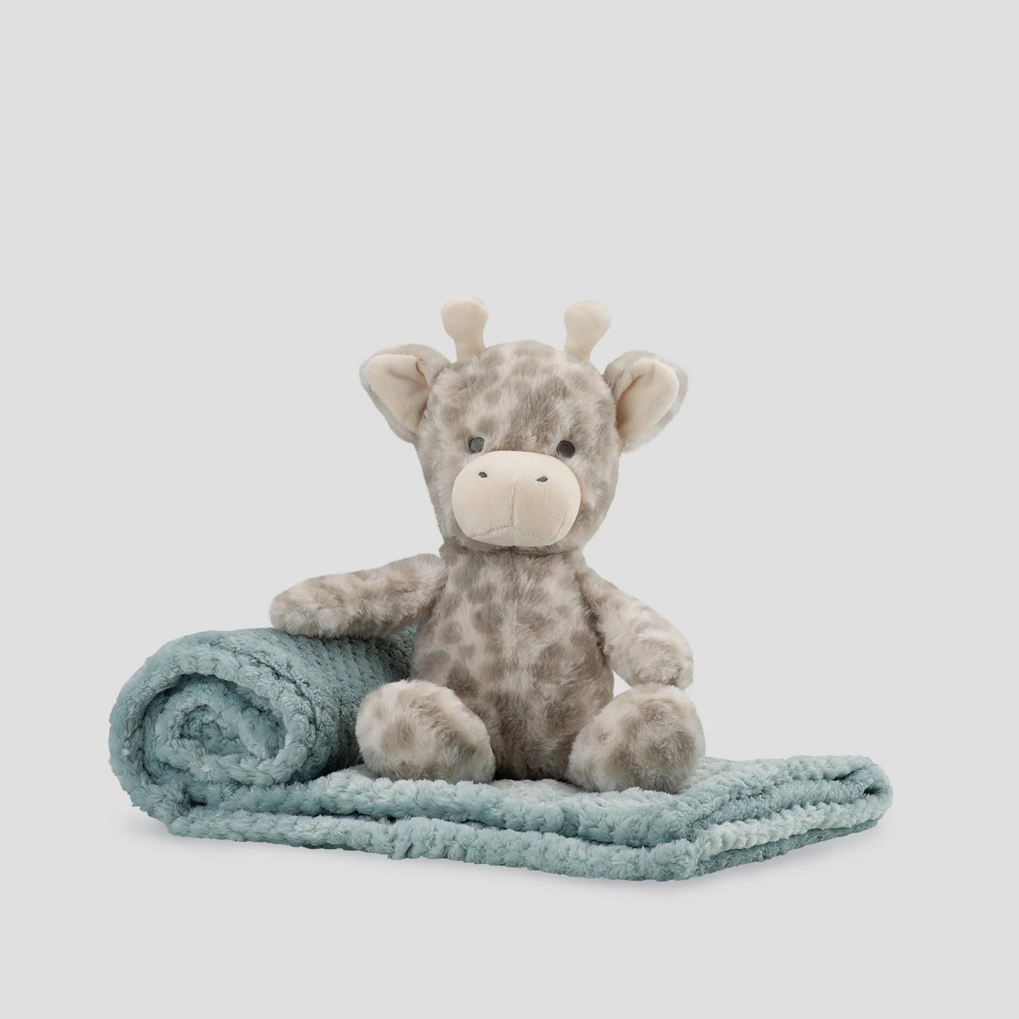 Plush giraffe toy with a light blue blanket on a white background