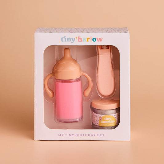 Baby gift set with pink sippy cup, bottle, and jar in a 'tiny harrow' box on a beige background