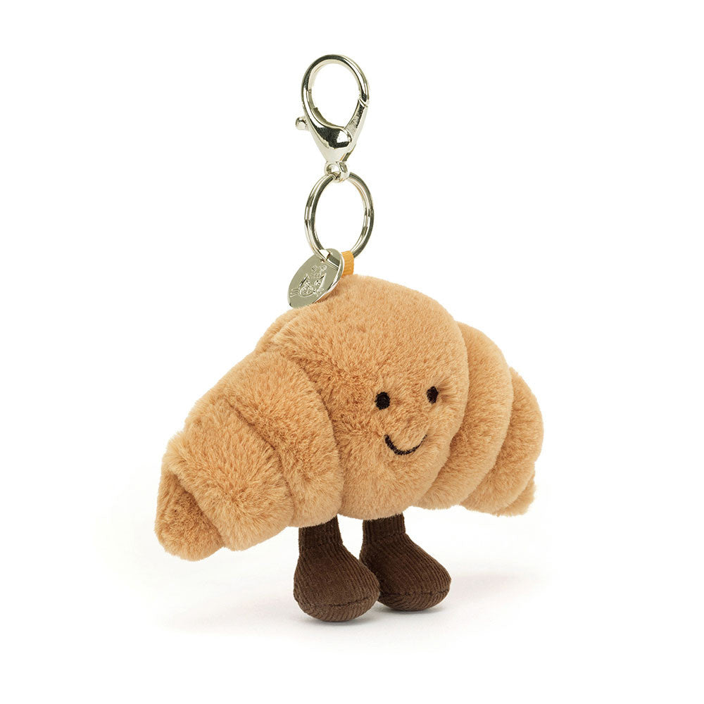 Plush croissant-shaped keychain with a smiling face on a white background