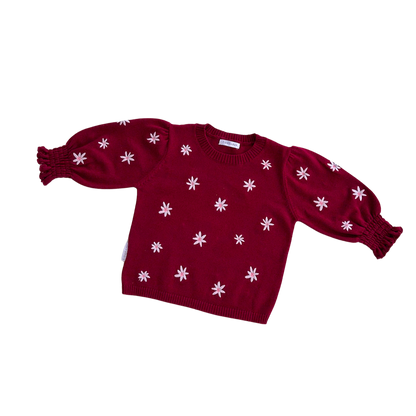 Red sweater with white floral patterns on a white background