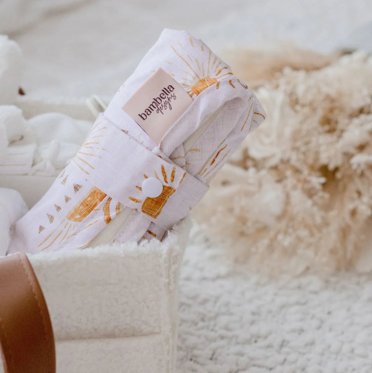 Baby swaddle with brand logo in a basket on a soft surface