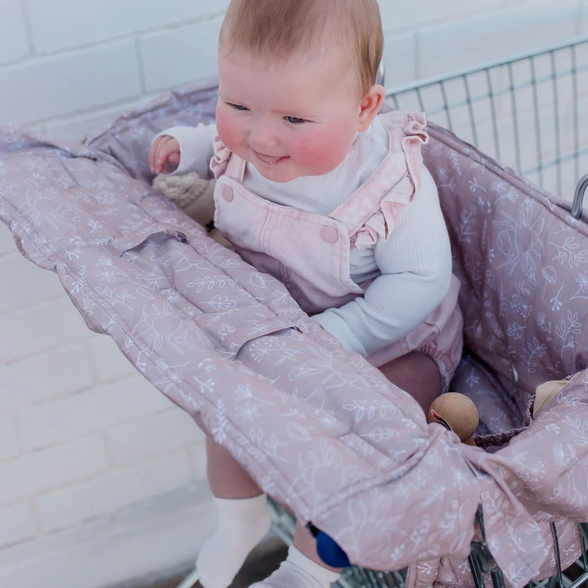 Baby in a pink stroller with a white tiled wall background