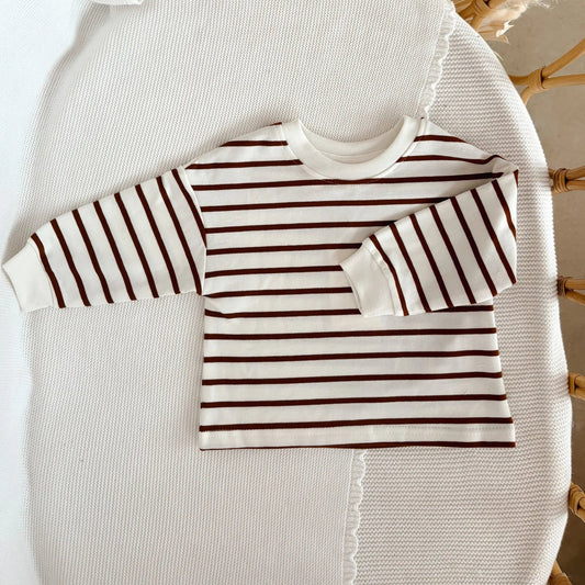 Striped shirt on a white cushion with a wicker chair in the background
