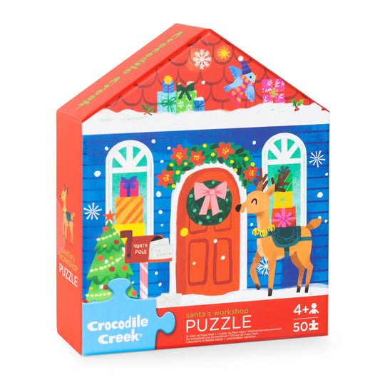 Crocodile Creek Santa's Workshop 50-piece jigsaw puzzle box, featuring a colorful illustration of a decorated Christmas house with a reindeer, tree, and gifts.