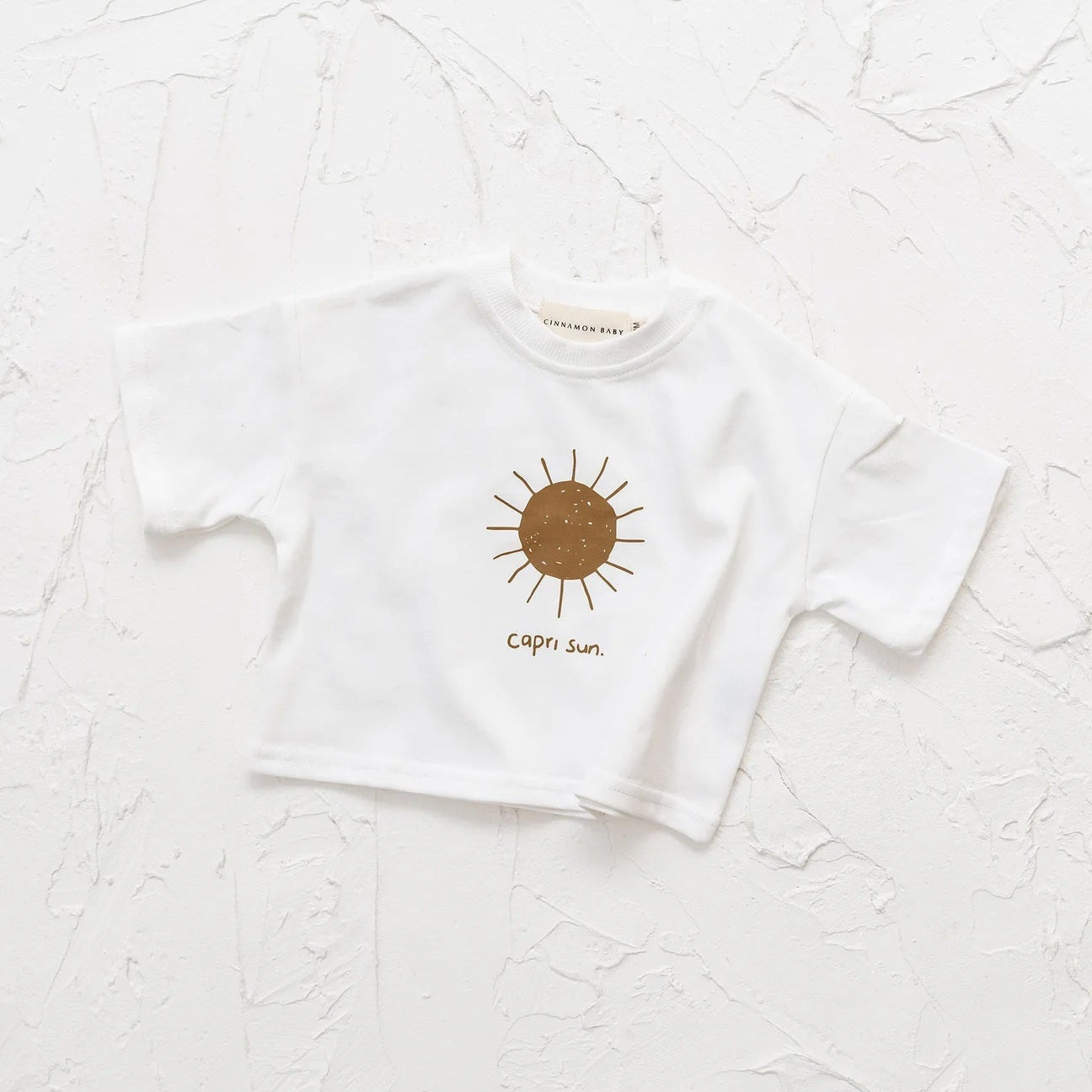 White t-shirt with a sun design and text on a textured white background