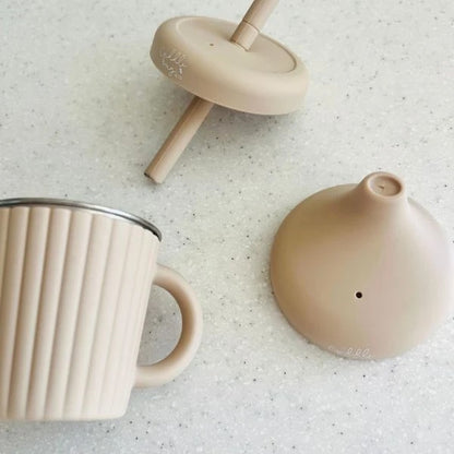 Beige mug, wooden top, and round object on a textured surface
