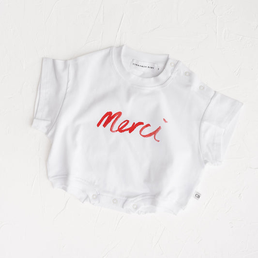 White t-shirt with red 'Merci' text on a white background