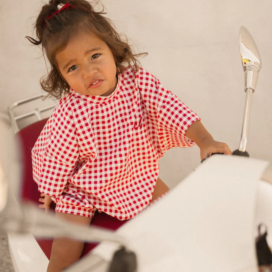 Child wearing a red and white checkered shirt on a motorcycle