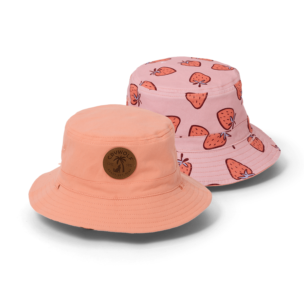 Two bucket hats, one peach and one pink with strawberry pattern, on a white background.