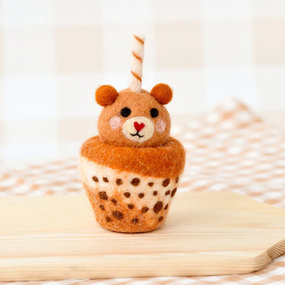 Plush toy resembling a bear in a cup with polka dot pattern on a wooden surface.