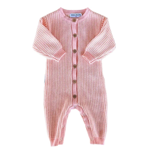 Pink knitted baby romper with button details on a light gray background