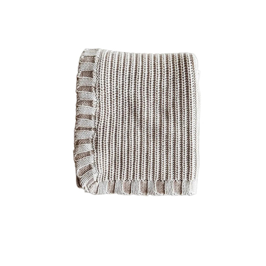 Textured blanket with fringe on a light gray background