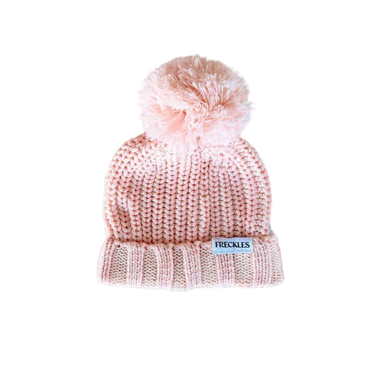 Pink knit beanie with pom-pom on a light gray background