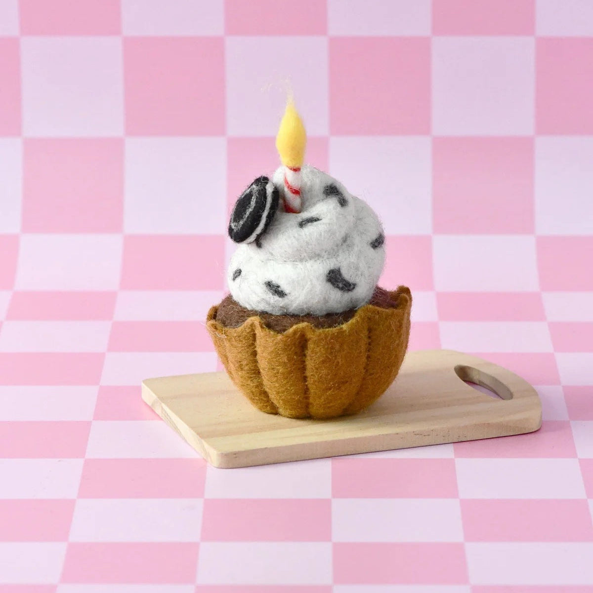 Felted ice cream cone with a candle on a pink checkered background