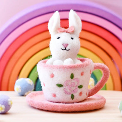 White plush bunny in a pink teacup with a rainbow background