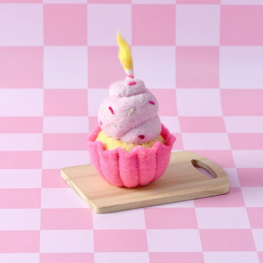 Pink cupcake-shaped bath bomb with a candle on a wooden board against a pink checkered background