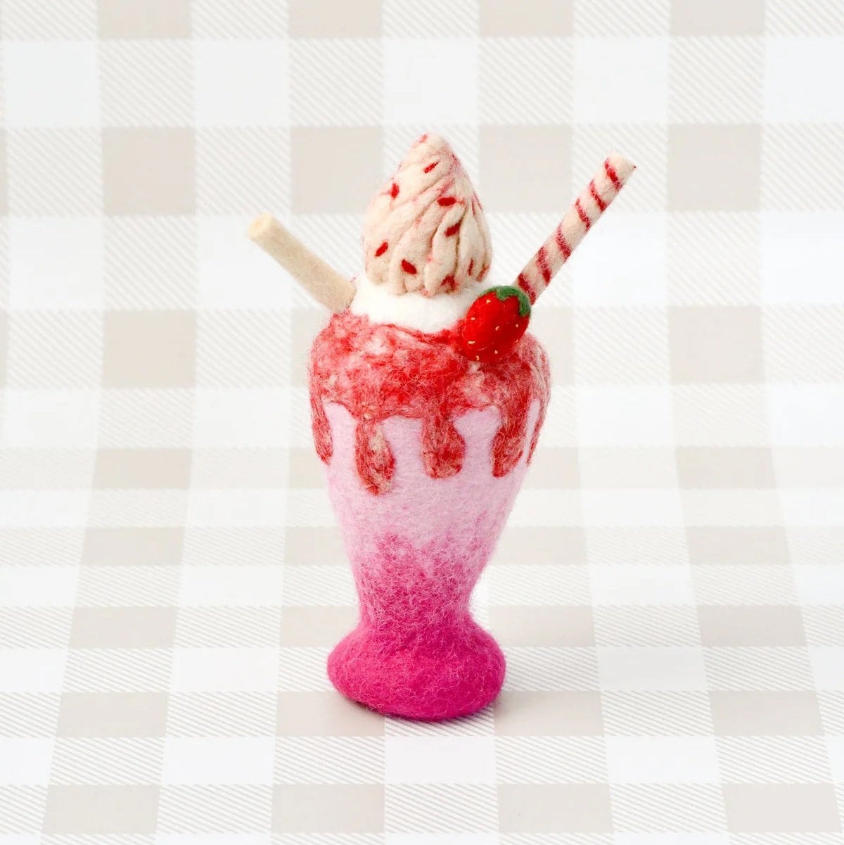 Pink and red milkshake with a cherry on top against a striped background